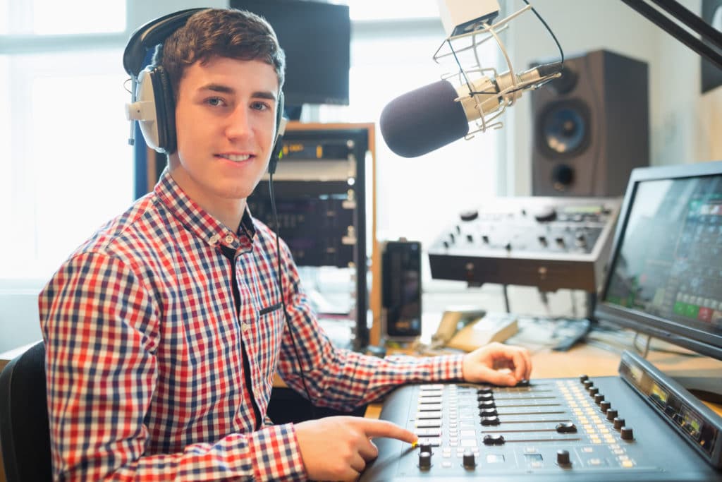 Portrait Of Radio Host Using Sound Mixer On Table In