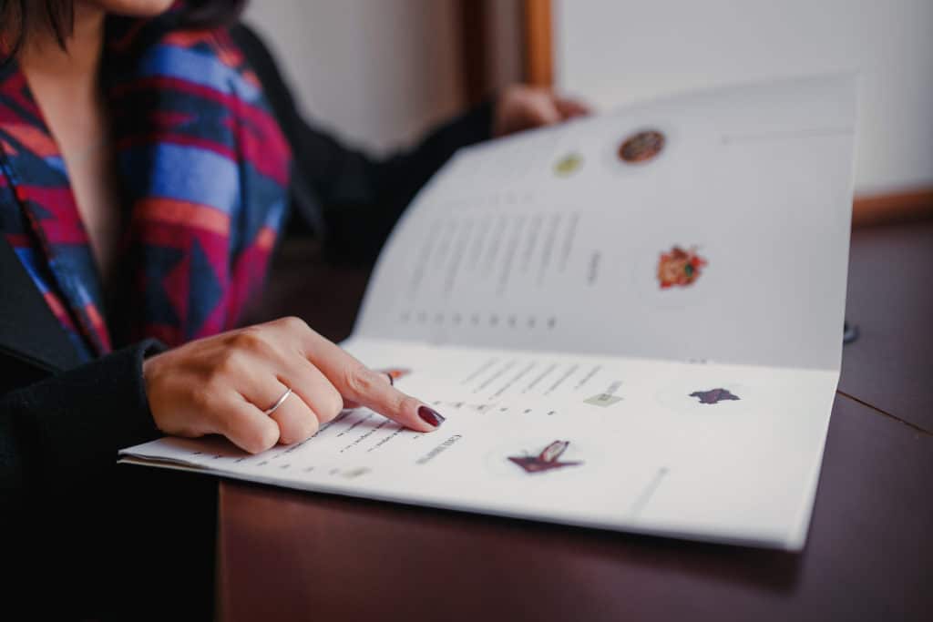 Close Up Of Woman Finger With Menu Choosing Dishes At