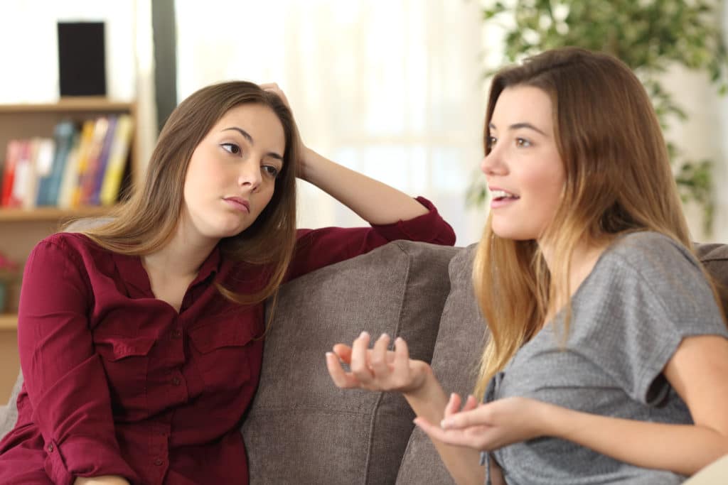 Bored Girl Listening To Her Friend Having A Conversation Sitting