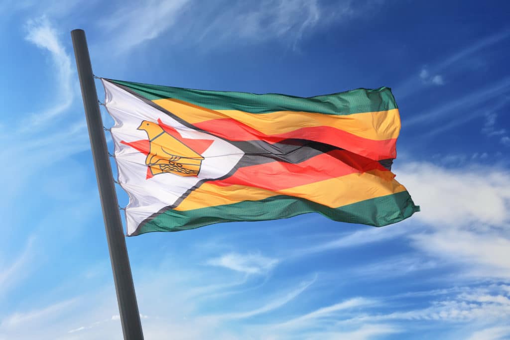 Flag Of Zimbabwe Against The Background Of The Blue Sky