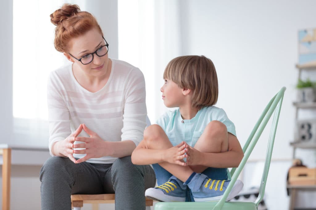 Young Female School Psychologist Having Serious Conversation With Smart Little