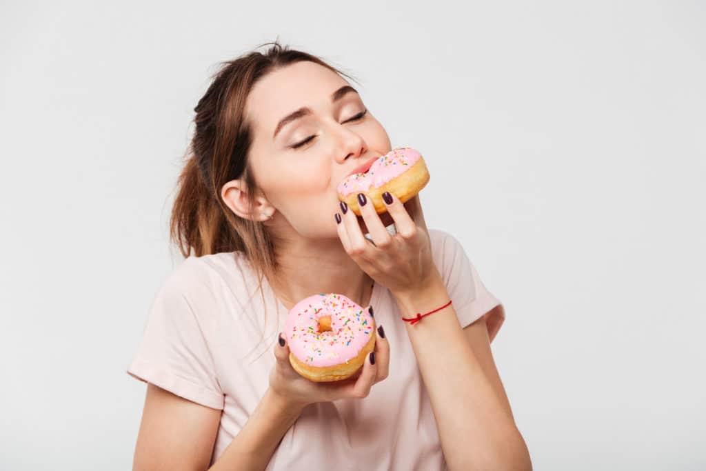 Close Up Portrait Of A Satisfied Pretty Girl Eating Donuts