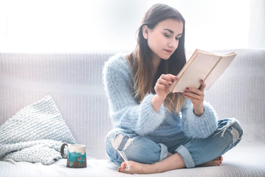 Beautiful Girl On A White Sofa Reading A Book