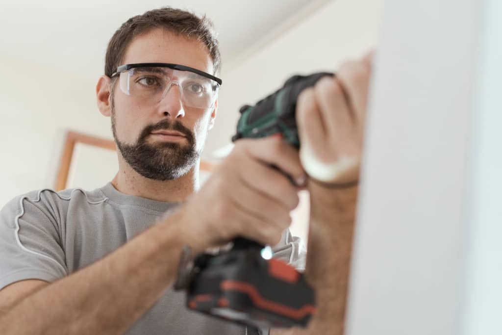 Professional Repairman With Protective Goggles He Is Using A Drill