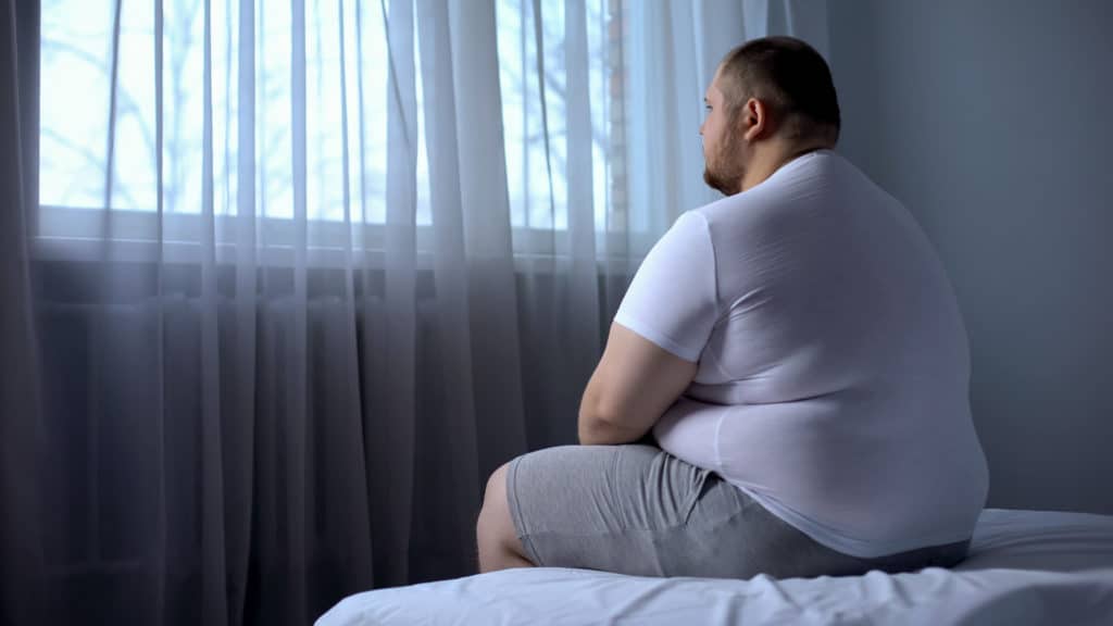 Sad Heavy Man Sitting On Bed At Home Health Problem 