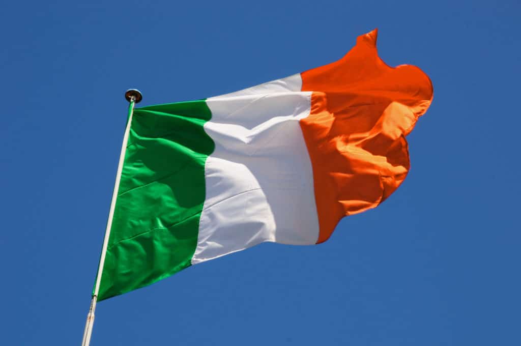 Irish Flag Fluttering In A Brisk Breeze Against A Bright