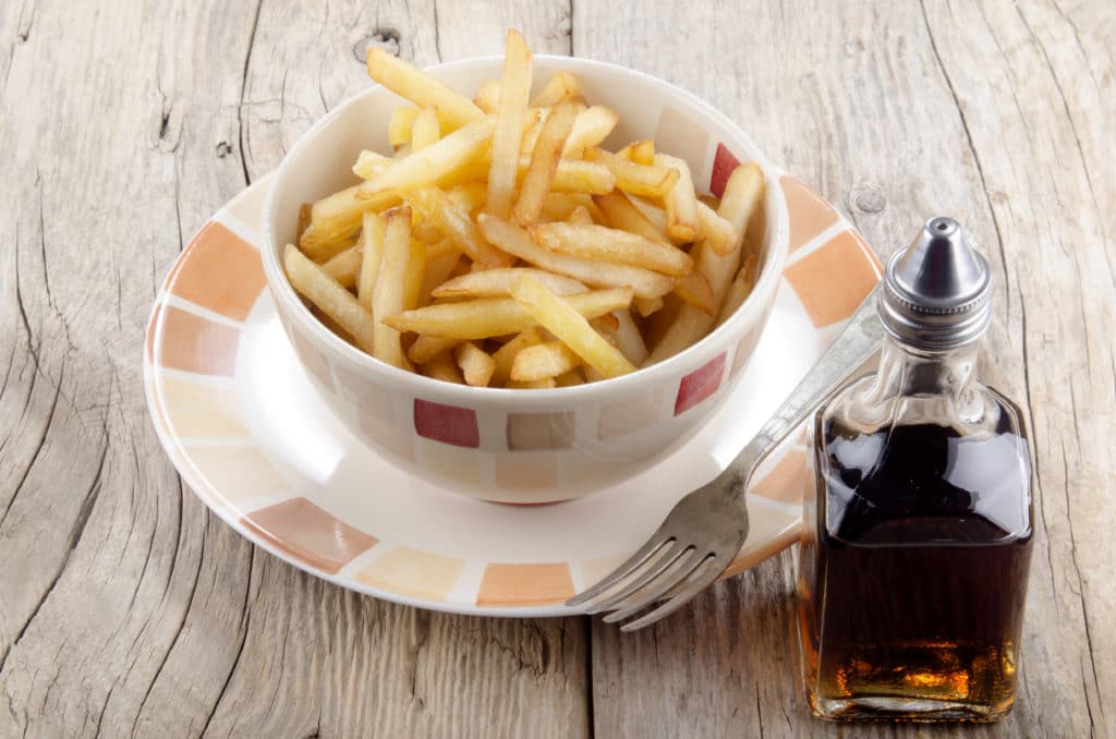 French Fries And Malt Vinegar On A Rustic Table