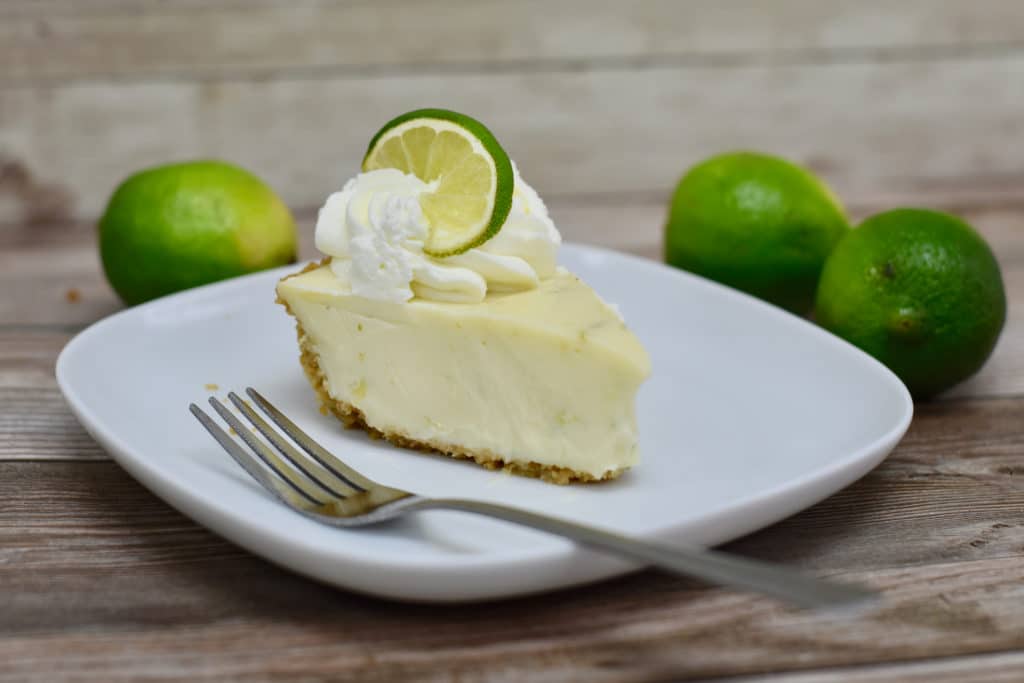 Slice Of Key Lime Pie On Plate With Limes
