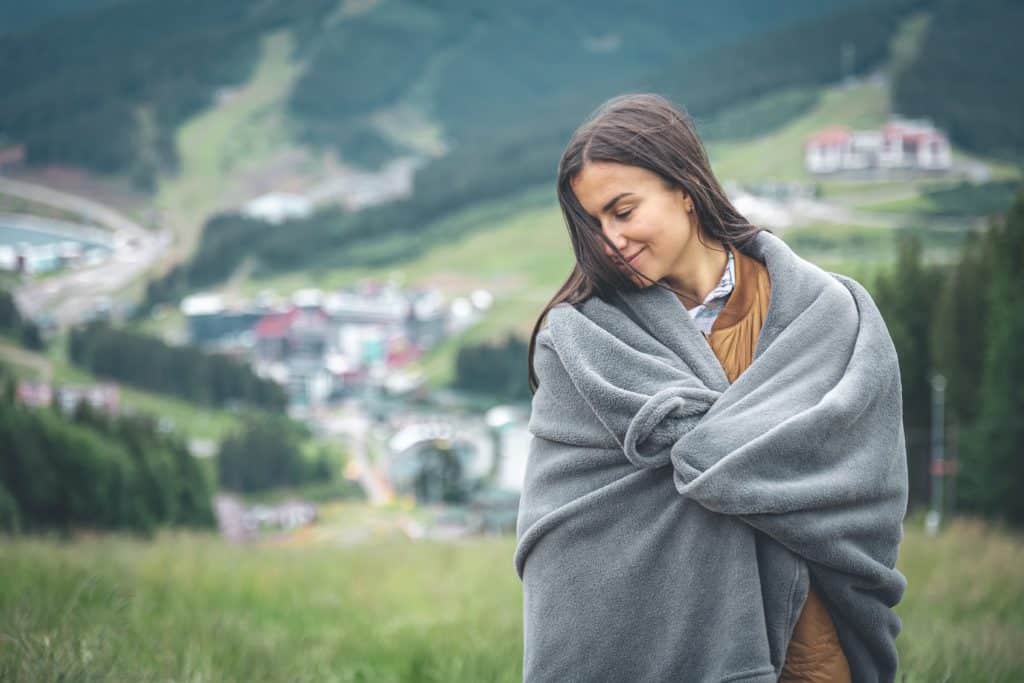 A Young Woman Wrapped In A Blanket In The Mountains.