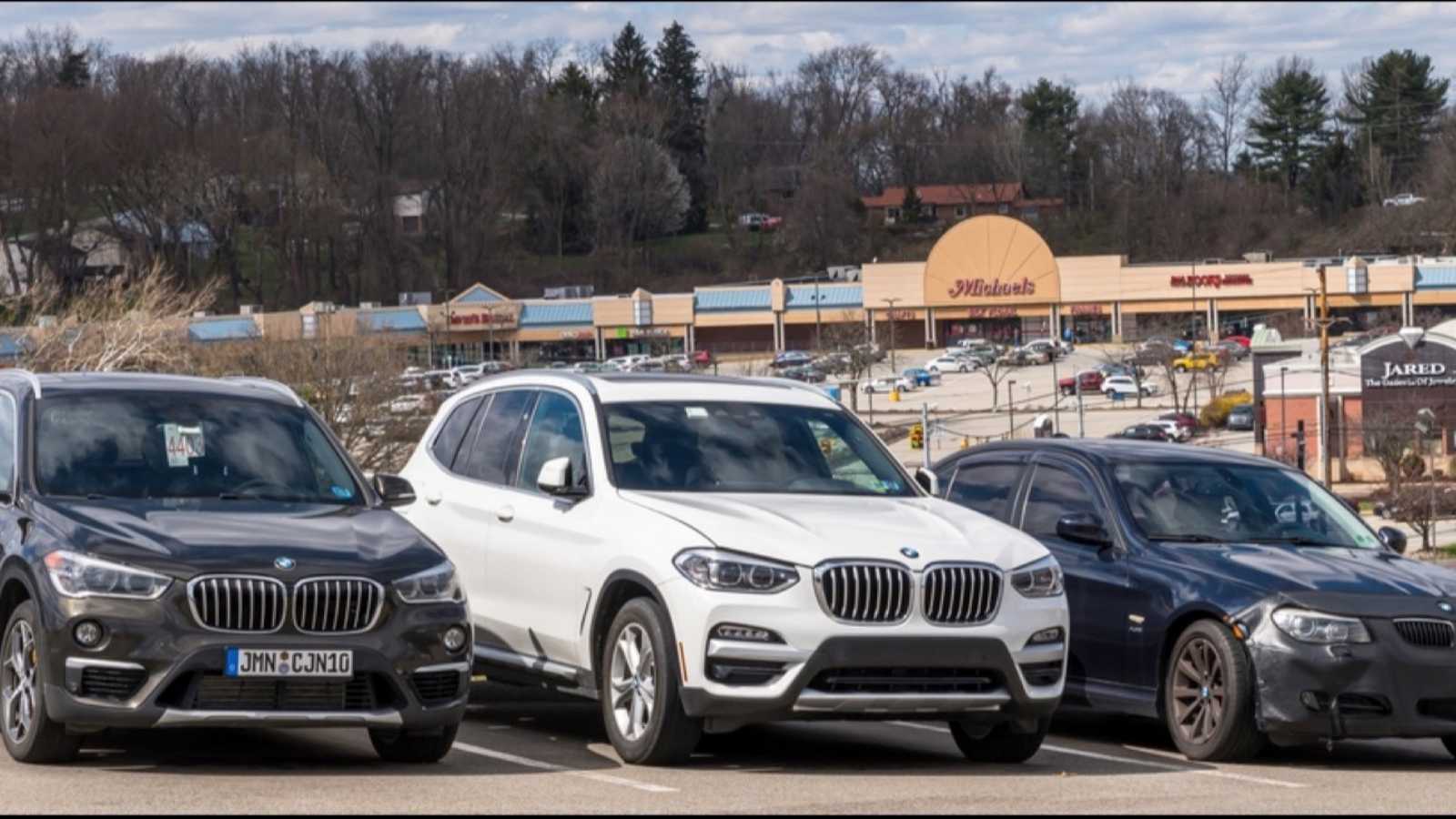 Monroeville, Pennsylvania, USA April 10, 2022 Three different BMW vehicles lined up at a dealership with a outdoor mall in the distance on a sunny spring day