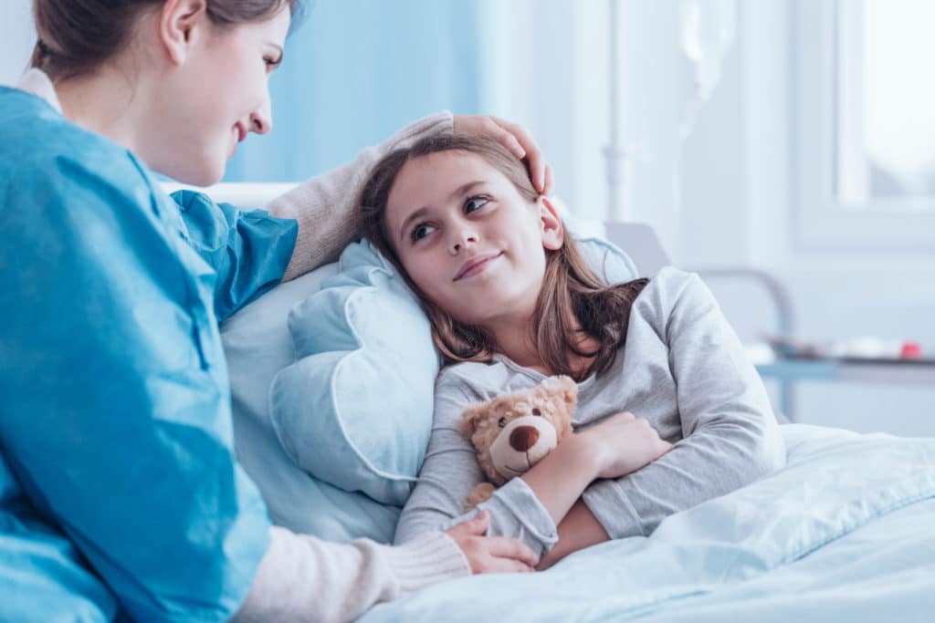 Smiling Caregiver Visiting Happy Sick Child In The Health Center