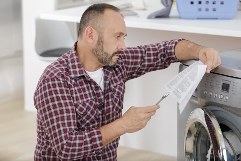 Man Installing A Washing Machine At Home