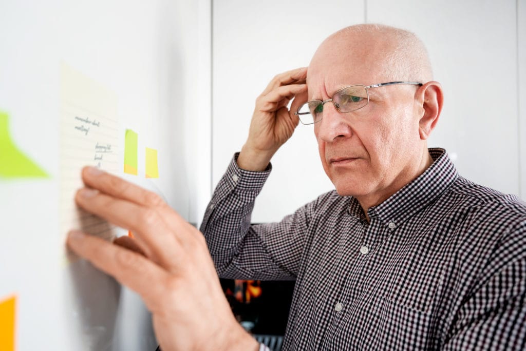 Elderly Man Looking At Notes. Forgetful Senior With Dementia Memory