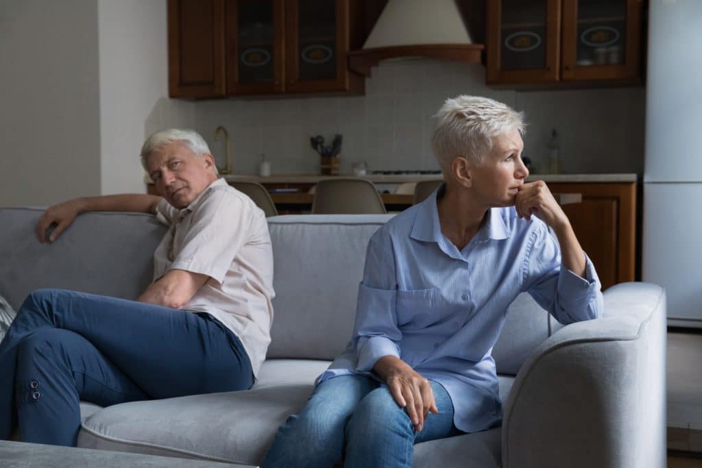 Thoughtful Older Married Couple Sit On Sofa Separately Feeling Frustrated