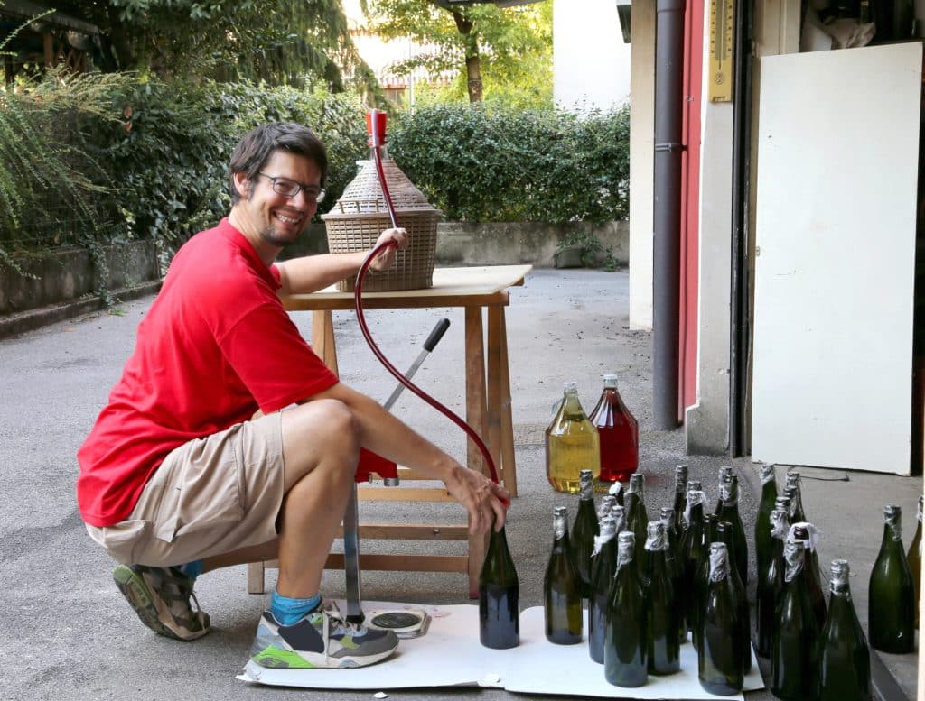 Young Man Smiling While Bottling The Wine At Home In