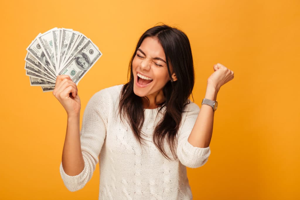 Portrait Of A Cheerful Young Woman Holding Money Banknotes And