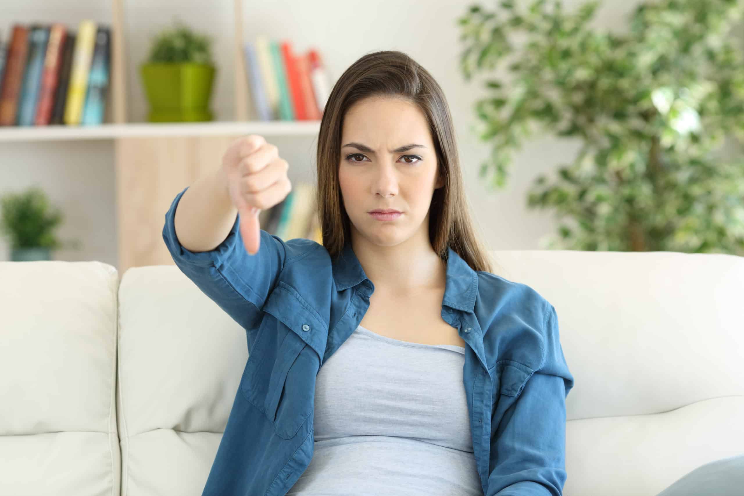 Angry Woman Looking At Camera With Thumbs Down Sitting On