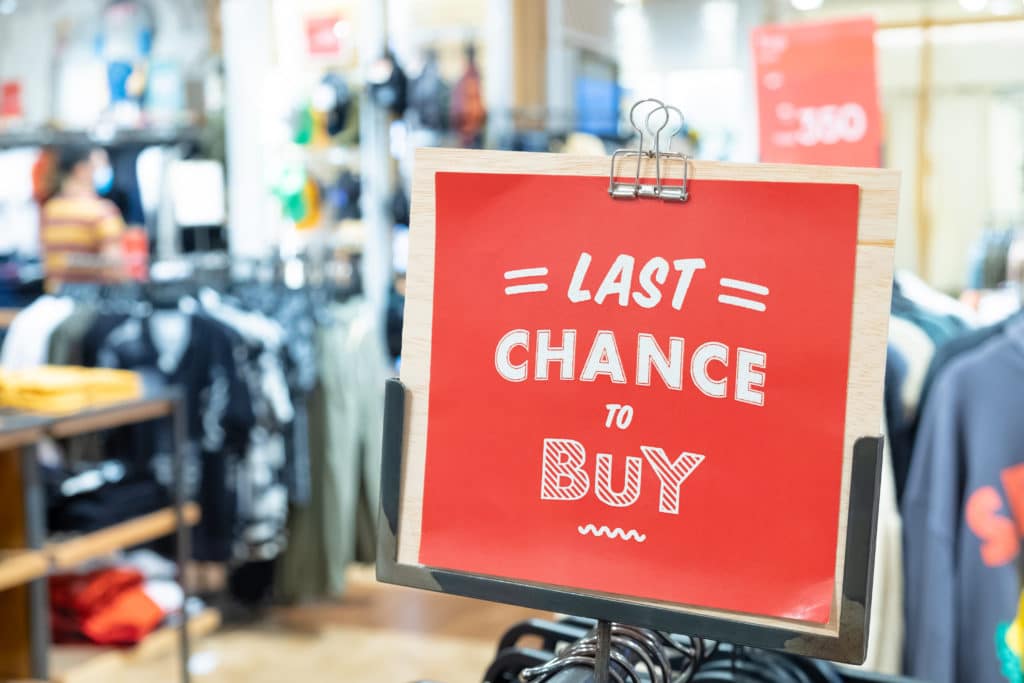 Red Last Chance To Buy Sign Inside Cloth Store During
