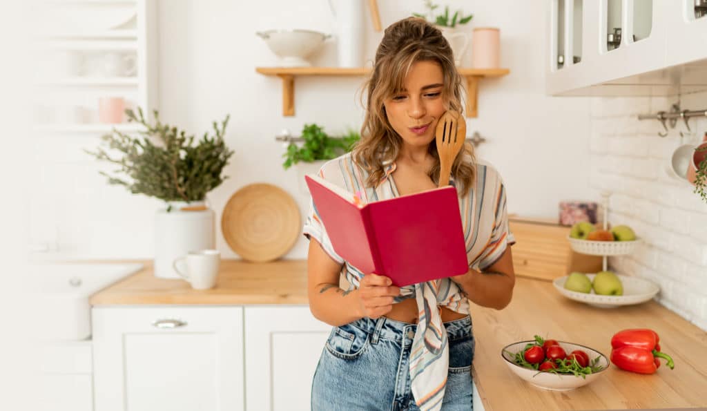 Funny Housewife Woman Looking At Recipe In Cookery Book Preparing