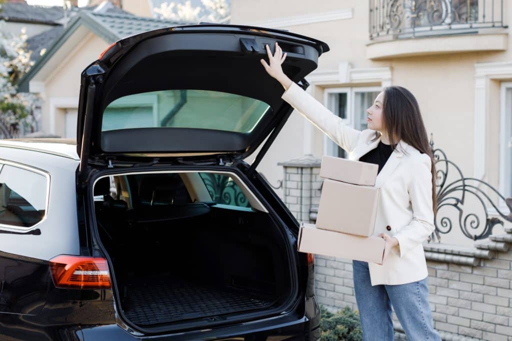 Young Business Woman Picking Up Parcels From A Car Trunk 
