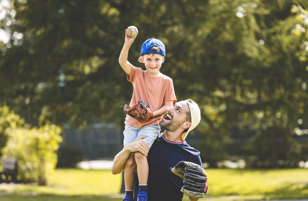 A Father And Son Playing Baseball In Sunny Day At