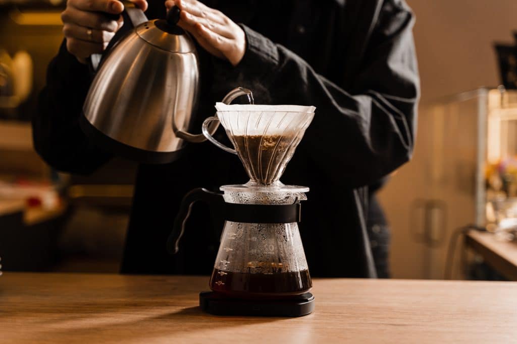 Drip Filter Coffee Brewing. Barista Pouring Hot Water Over Filter