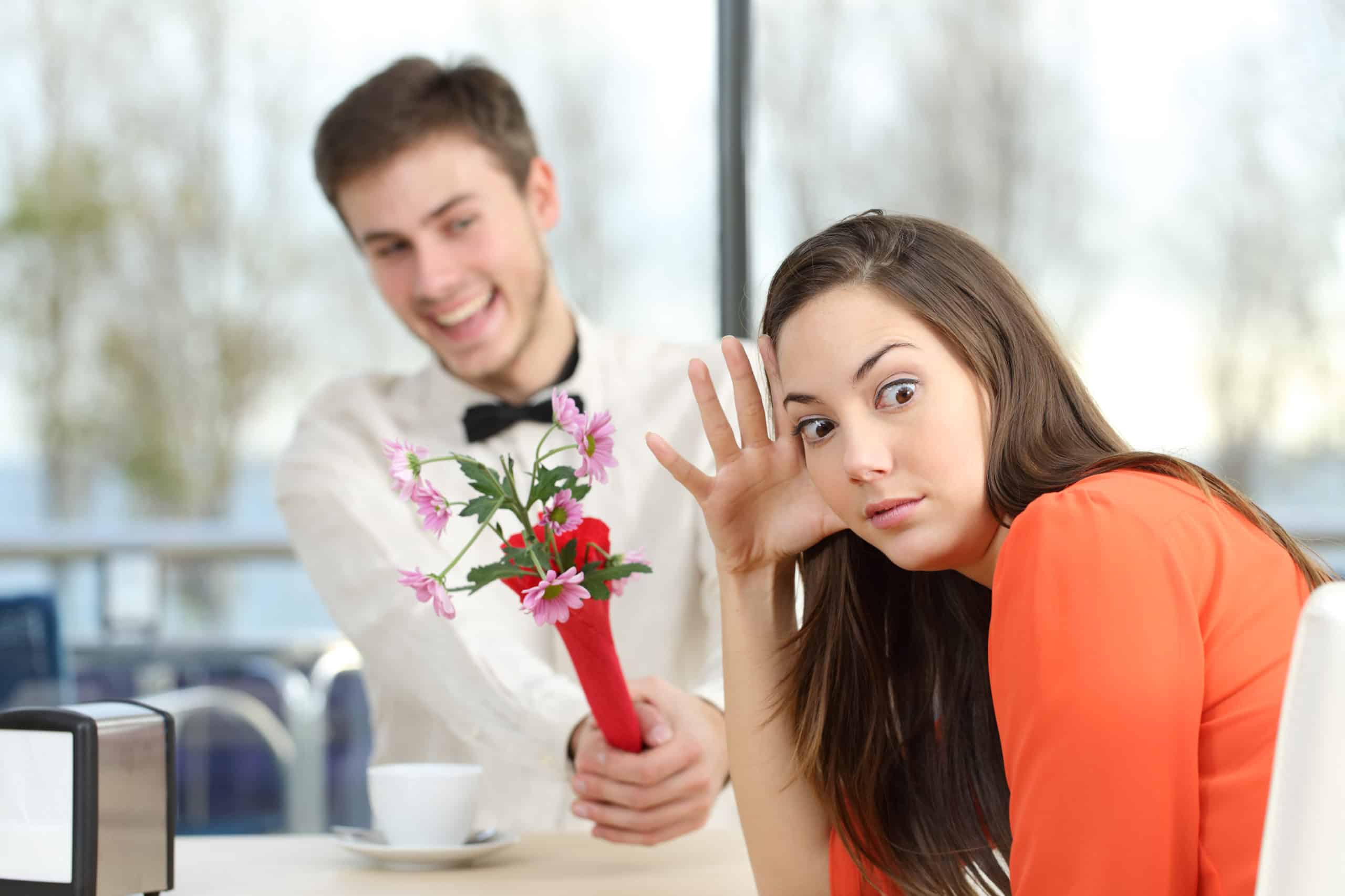 Disgusted Woman Rejecting A Geek Boy Offering Flowers In A