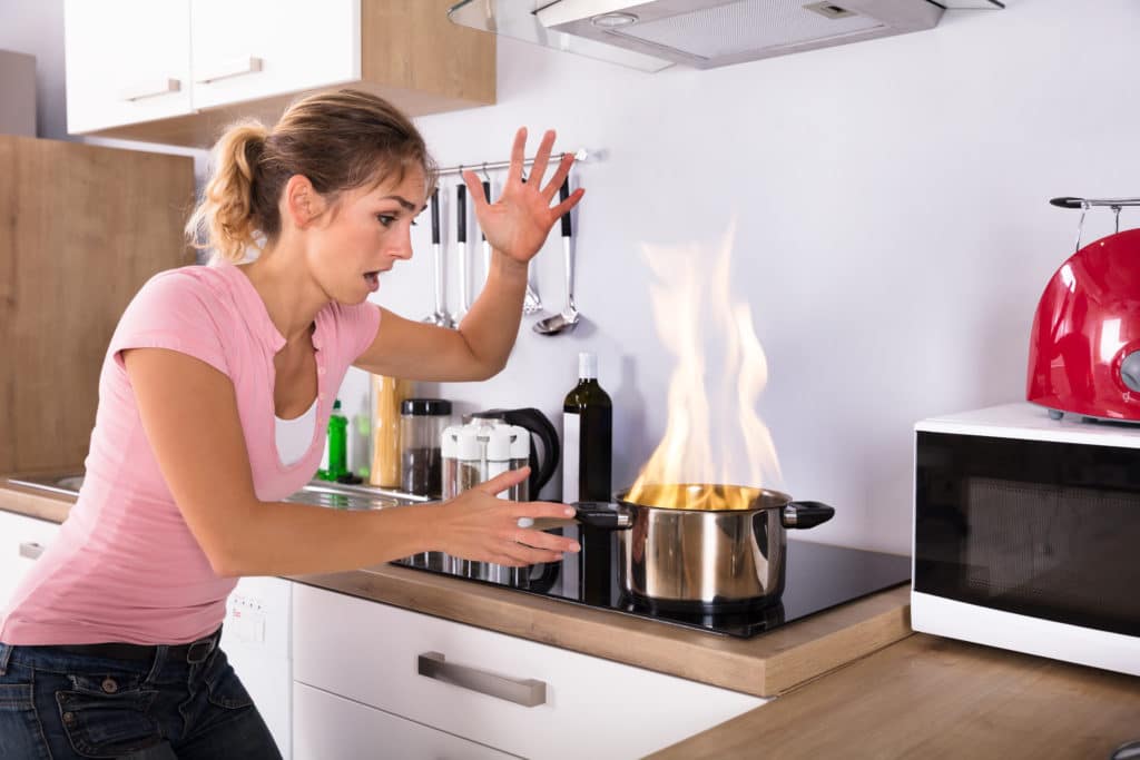 Shocked Young Woman Looking At Cooking Pot With Fire Near