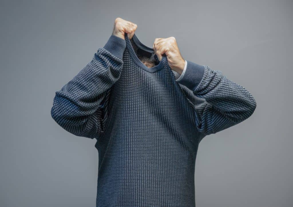 Man Taking Off Sweater Isolated On Gray Background