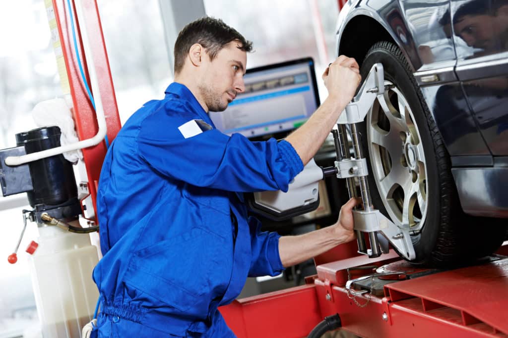 Car Mechanic Installing Sensor During Suspension Adjustment And Automobile Wheel