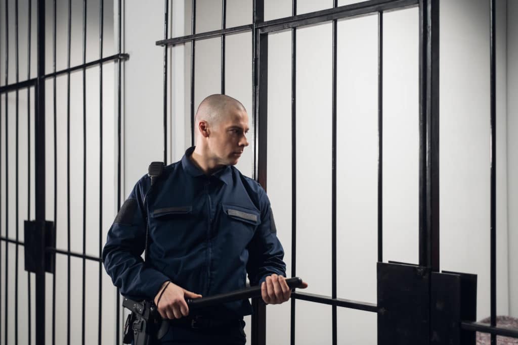 A Strict Prison Guard In Uniform Guards Cells With Prisoners