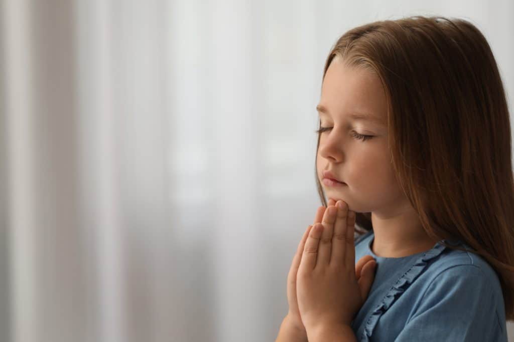 Cute Little Girl With Hands Clasped Together Praying Indoors. Space