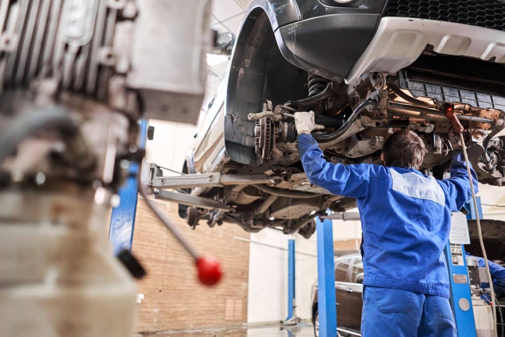 Car Mechanic Inspecting Car Steering Rod And Repair Suspension Detail.