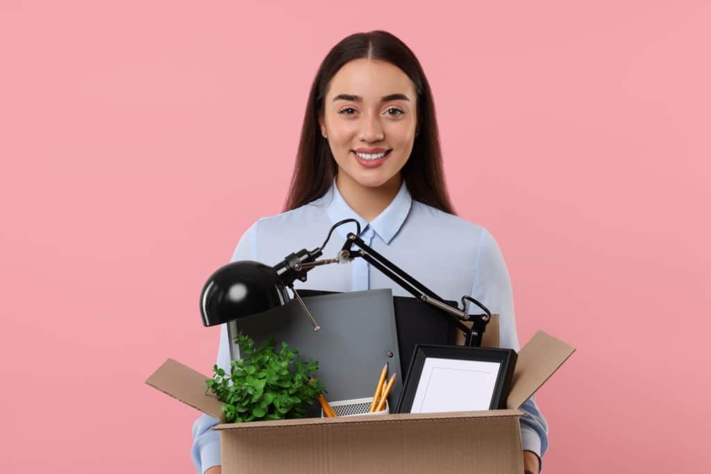 Happy Unemployed Woman Holding Box Of Personal Office Belongings On