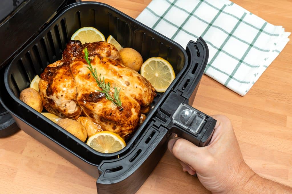 Hand Cooking Whole Roasted Chicken With Garnish In Air Fryer