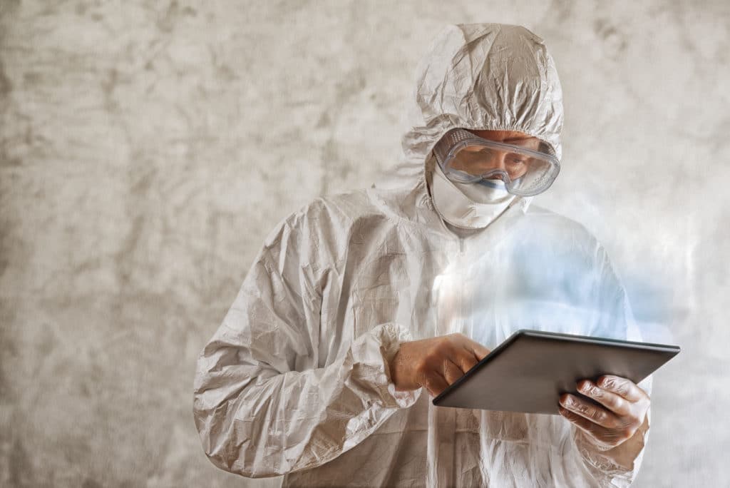 Chemical Scientist In Protective Laboratory Clothing Using Digital Tablet Computer