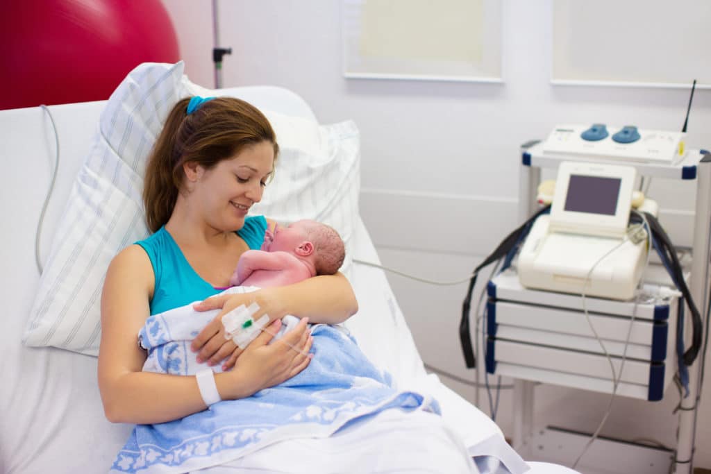 Mother Giving Birth To A Baby. Newborn Baby In Delivery
