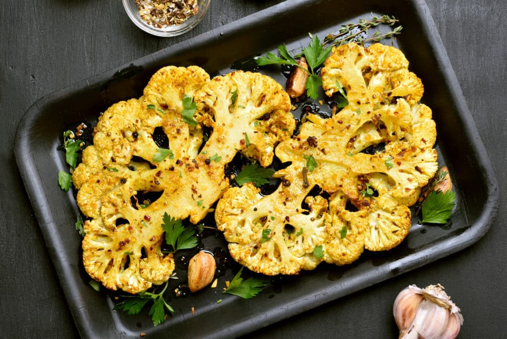 Baked Cauliflower Steaks With Herbs And Spices On Baking Sheet