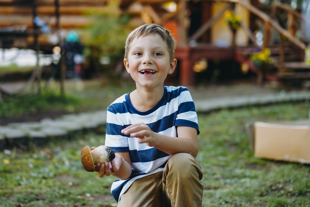 Portrait Of Cute Caucasian Boy Sitting On Haunches On The