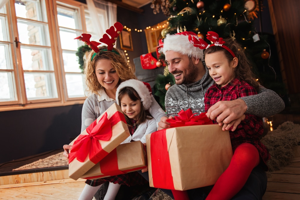 Family Of Four Celebrating Christmas Exchanging Presents