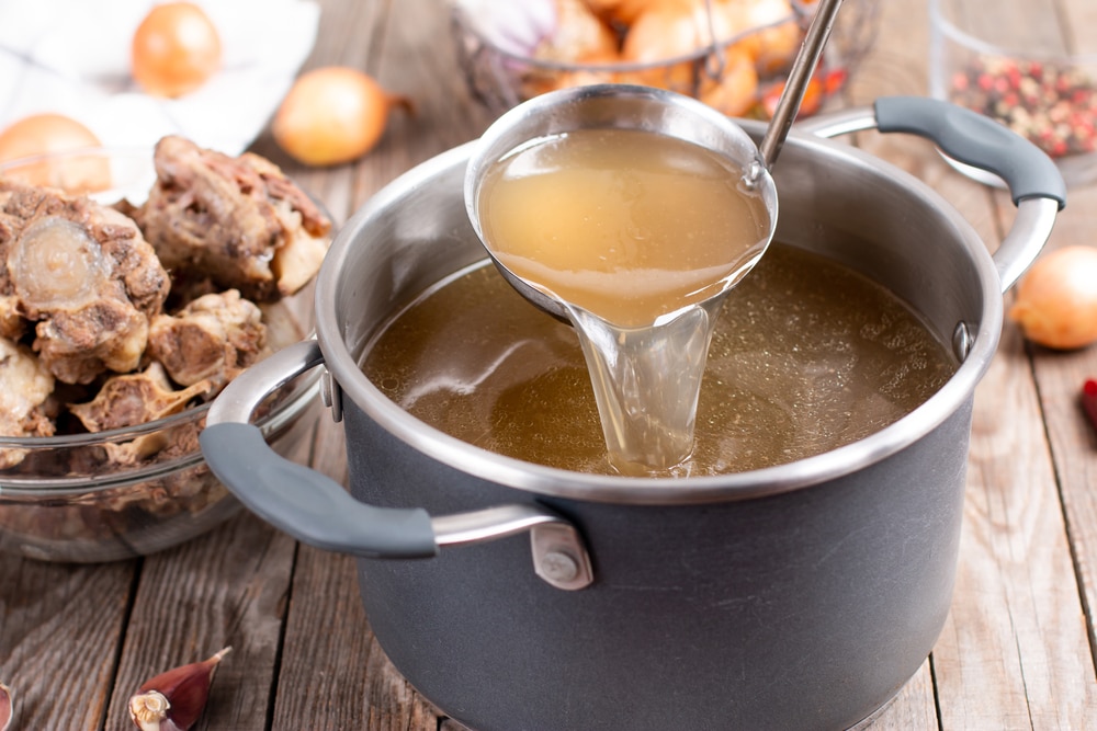 Saucepan With Bouillon With A Ladle On The Table. Bone