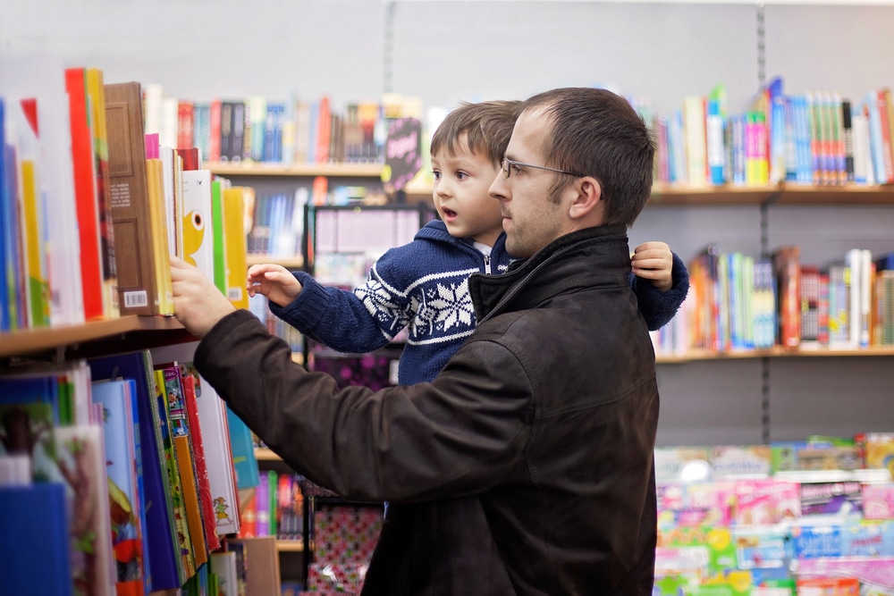 Adorable Little Boy Sitting In A Book Store Looking At